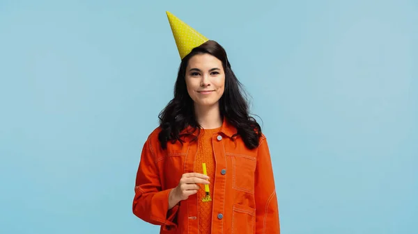 Felice giovane donna in giacca arancione e cappello tenuta corno partito isolato su blu — Foto stock