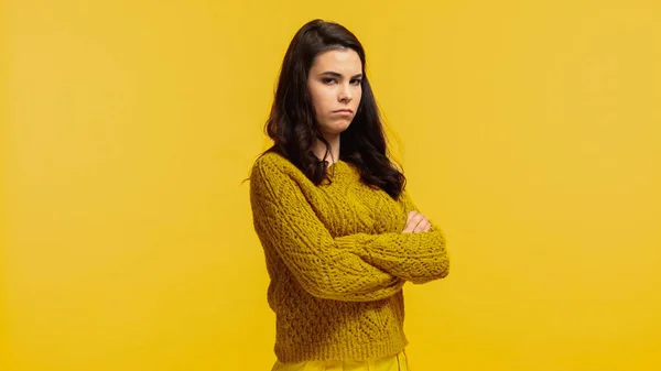 Beleidigte junge Frau im herbstlichen Pullover mit verschränkten Armen auf gelbem Grund stehend — Stockfoto