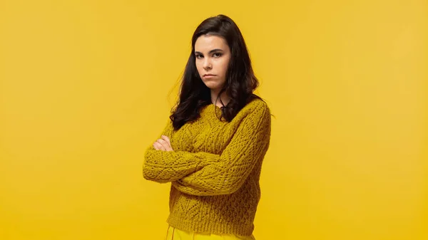 Traurige junge Frau im herbstlichen Pullover, die mit verschränkten Armen auf gelb steht — Stockfoto