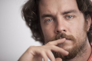 Man with thoughtful expression and gray eyes. Serious man covering his lips with a finger.