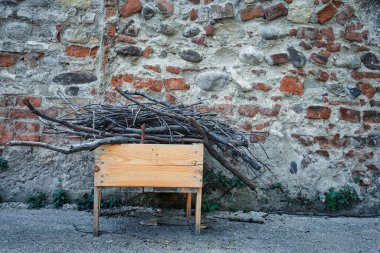 A box full of wood collected in front of a wall.An orange wooden box contains dry twigs. Still life photography and cold colors.