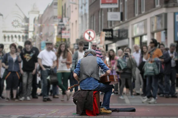 Street guitarist performs in front of a crowd.Talented folk musician plays the guitar on his lap in the streets of Dublin.