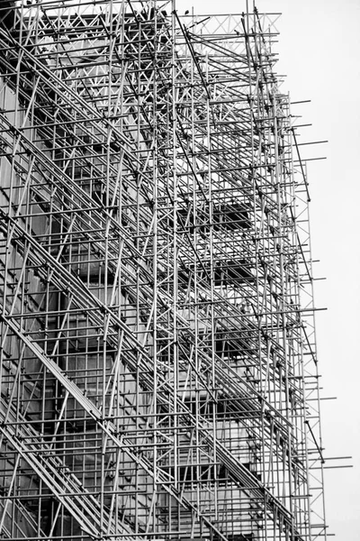 Huge scaffolding to renovate the facade of a castle. Dense structure of pipes and poles. Architecture, restoration and work in progress.