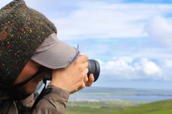 Young photographer takes a panoramic photo. Closeup of a man using a photocamera. Phorography in a national park.