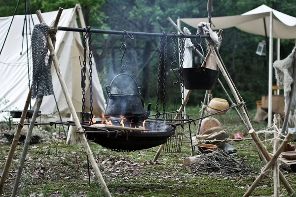 Ancient pot is heating up on fire. old lifestyle. Smoke comes out of the embers of an old brazier. Lunch time during a celtic festival.