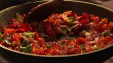 Tavada sıcak pepperoni. Chili con carne hazırlığı. Ahşap bir kaşığa yakın çekim. Biber ve soğanları karıştırıyor..