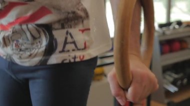 Strong and muscular calisthenics athlete holds gymnastic rings. Sporty man lifts himself up with great effort using wooden rings in the gym. How to false grip during muscle up workout.