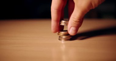Hand stacks some European coins. Man's hand collects and plays with coins of 50 cents, one and two euros. Wealth, investment and money. Slow motion 4k video.
