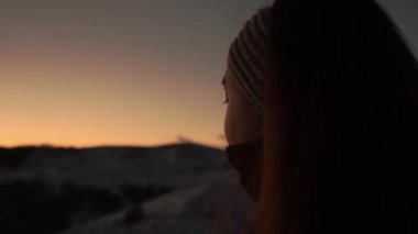 Girl watching beautiful sunset at mountain top. Girl's head shot from behind. Romantic scene. A woman thinks looking at the sun.