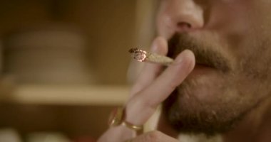 Man smoking a joint. Young man with mustaches blows O's smoking rings. Blurred video of a smoking man.