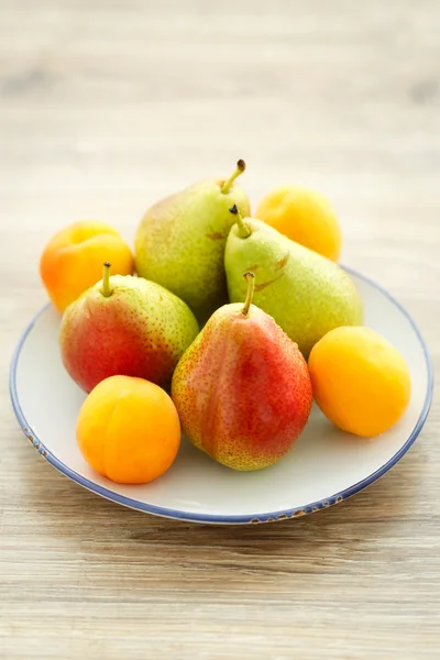 Placa de deliciosas peras frescas y albaricoques Imagen de stock