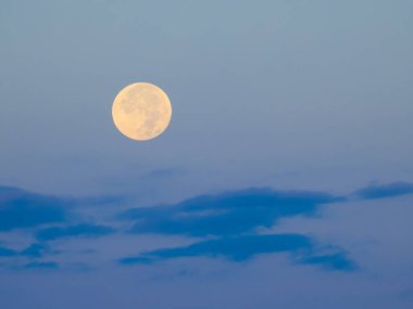 Dolunaya karşı şafak vakti gökyüzü ve mavi bulutlar.