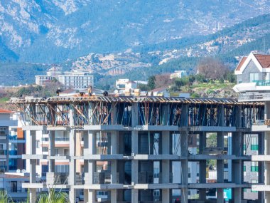 ALanya, Turkey - 10 Şubat 2022. Taurus dağlarının arka planına karşı inşa halinde olan çok katlı bir bina.