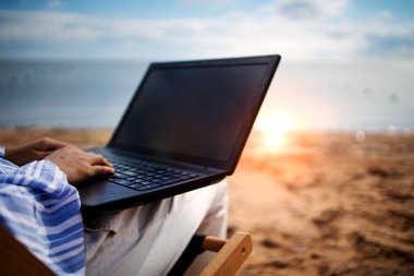 Plaj tatili sırasında tablet bilgisayarlı genç Asyalı kadın. Dizüstü bilgisayarda çalışan serbest çalışan, güneşlenip uzanan biri..