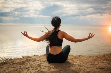 Güzel Asyalı kadın uçurumun kenarında yoga yapıyor. Deniz kenarında muhteşem bir manzaranın arkasında.. 