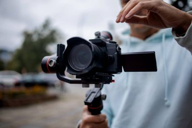 3 eksenli titreşimli dengeleyicide profesyonel kamera tutan genç profesyonel kameraman. Pro ekipmanlar titremeden yüksek kaliteli video yapmaya yardımcı olur.
