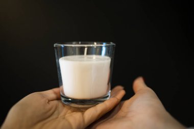 Siyah arka planda cam kavanozda beyaz el yapımı mum..