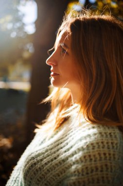 Gün batımında genç ve güzel bir bayan. Sarı saçlı ve kahverengi gözlü. Ilık sonbahar. Ilık bahar, güneş ışınları arkadan.