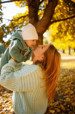 Genç anne ve küçük oğlu, parktaki sonbahar gününün tadını çıkarıyorlar.