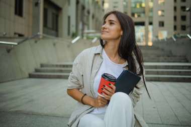 Dışarıda yürüyen ve gülümseyen bir iş kadınının portresi.