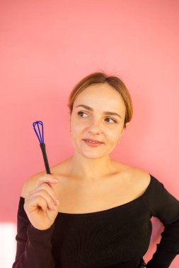 Çizgili önlüklü, sarışın, genç, yetişkin bir şekerci. Mangır ve corolla karışımı bir şey yapıyor. Pembe arka planda kapalı stüdyo çekimleri.