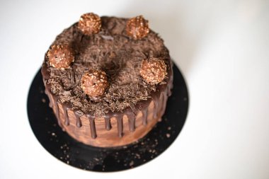 Erimiş siyah çikolatayla süslenmiş yumuşak çikolatalı pasta, beyaz masanın üzerinde kek parçaları ve şekerler. Boşluğu kopyala.