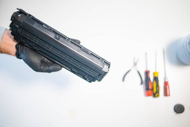 Hizmet merkezi ve atölye konsepti. Yazıcı için şarjör dolduran adam. Mürekkep şişesi beyaz masada. Tamirci eldivenle tamir ediyor..