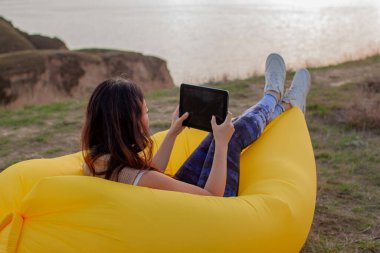 Dijital tablet kullanan genç Asyalı kadın tatilde dışarıda vakit geçiriyor..