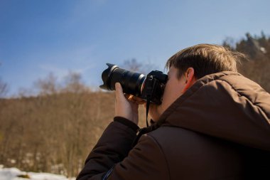 Kameraya bakan ve dijital kamerada fotoğraf çeken adam kar yağıyor ve insan güzel kış manzarasının tadını çıkarıyor..