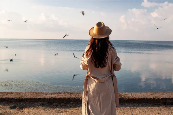 Genç kadın kış deniz sahilinde martıları besler. Kızla harika bir sahil sahnesi. Özgürlük, seyahat, uçma kavramı. Yaşam tarzı anı.
