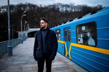 Yakışıklı sakallı adam metro tren bekliyor.