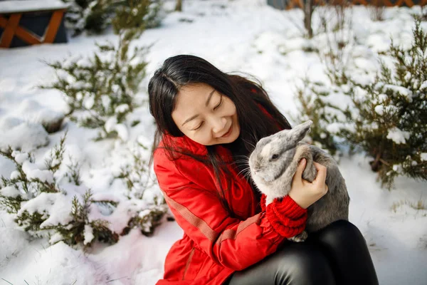 亚洲女孩抱着一只兔子在雪地的森林里 与复活节兔子的友谊 — 图库照片