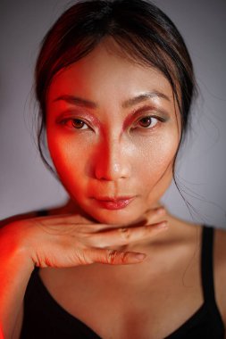 Moda mankeni, neon renkli parlak ışıkları olan Asyalı bir kadın stüdyoda poz veriyor. Moda makyajlı güzel seksi bir kızın portresi.