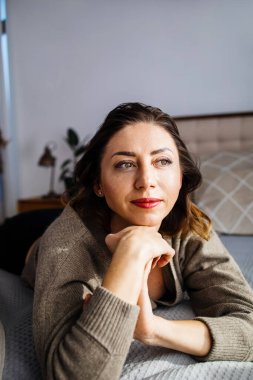 Evdeki rahat bir oturma odasında ciddi ve düşünceli bir kadının portresi..