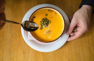 Ellerinde bir kase sıcak kabak çorbası. Bir kase vejetaryen kabak çorbası tutuyorum. Rahatlatıcı yemek. Tonlu resim, seçici odak