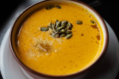 Balkabağı ve havuç çorbası, koyu ahşap arka planda kremalı ve maydanozlu tadka. Yukarıdan görüntüle.