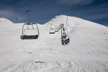 Güneşli bir akşamda Alp Dağları 'nda kayak asansörü boş. İnsanların kayak ve snowboard yapmaktan hoşlandığı teleferik kablosu..