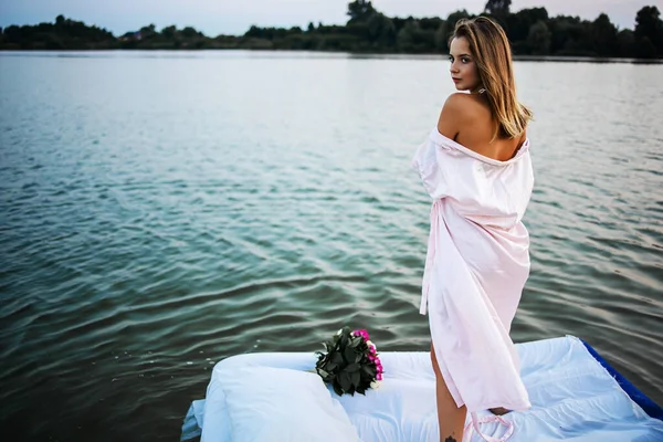 日落时 一个穿着粉色浴衣的漂亮金发姑娘站在湖边 童话故事 — 图库照片