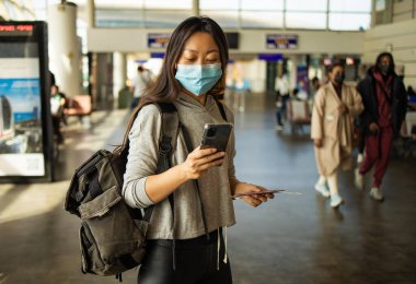 Havaalanında cep telefonu kullanan Asyalı kadın.