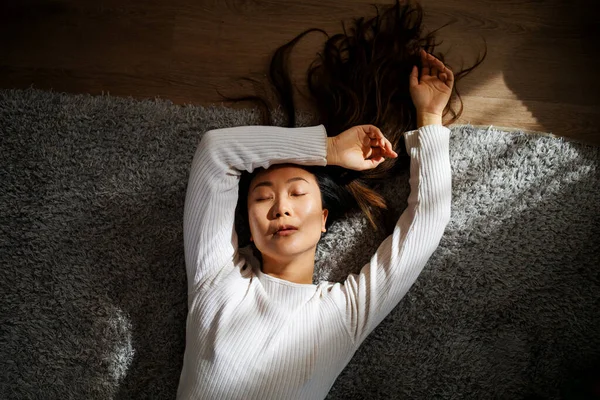 官能的な若いですアジアの女性とともに閉じられた目は太陽の光の下でベッドに横たわって — ストック写真