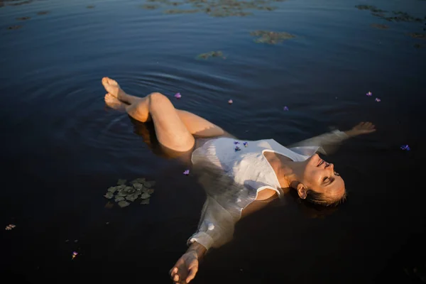 美丽的年轻女子在湖中漂浮的白衣服上放松身体和头脑 — 图库照片