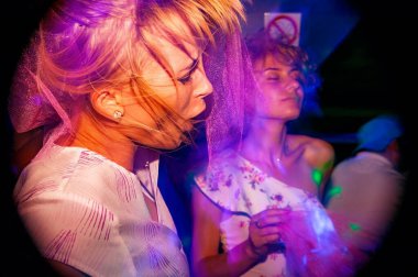 Konserdeki kalabalık, renkli sahne ışıkları içinde tezahürat yapan bir kalabalık. Mutlu arkadaşlar tatil ışıkları olan bir kulüpte dans ediyorlar..