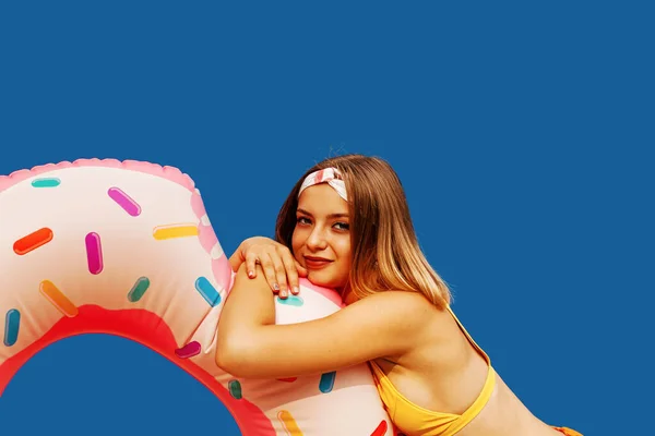 一个穿着泳衣的笑女孩的画像 带着一个蓝色背景的充气环 — 图库照片