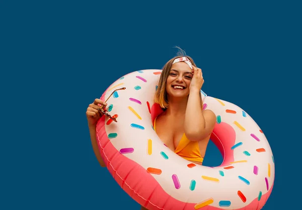 一个穿着泳衣的笑女孩的画像 带着一个蓝色背景的充气环 — 图库照片