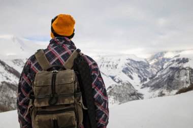 Sırt çantalı aktif turist karlı dağın tepesindeki manzaranın tadını çıkarıyor.