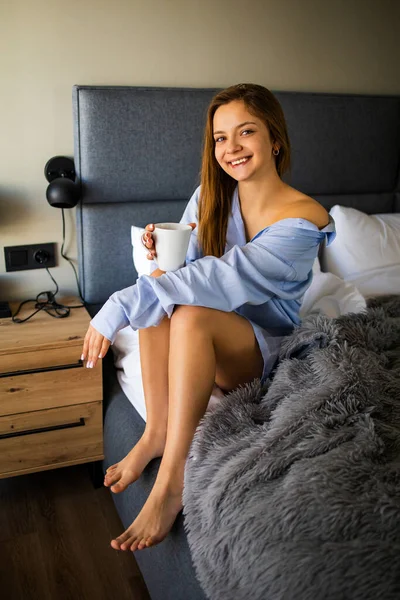 Image Beautiful Young Woman Blue Shirt Smiling Drinking Tea Bed — 스톡 사진