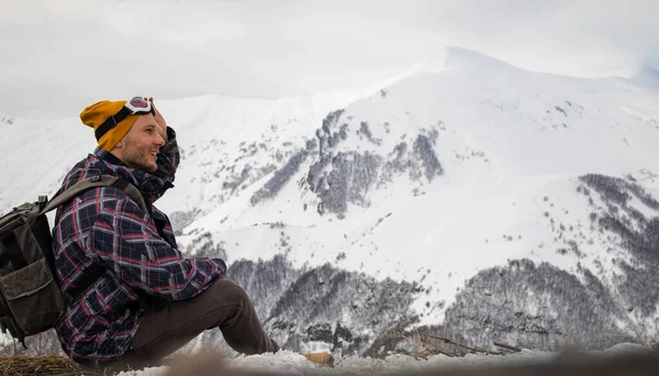 Sırt çantalı aktif turist karlı dağın tepesindeki manzaranın tadını çıkarıyor.