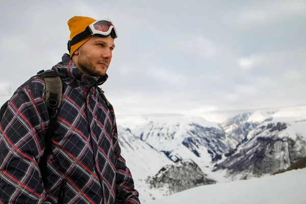 Sırt çantalı aktif turist karlı dağın tepesindeki manzaranın tadını çıkarıyor.