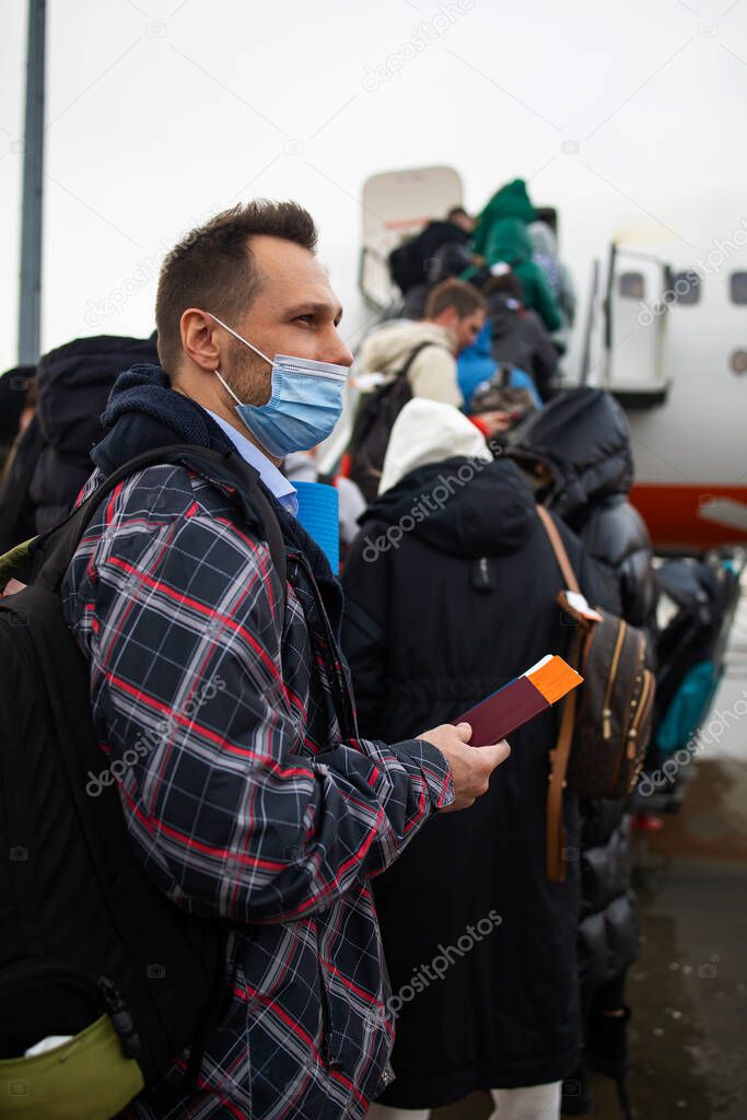 Passengers board the plane. Masked people board the flight. Travel during quarantine. A passenger in mask.