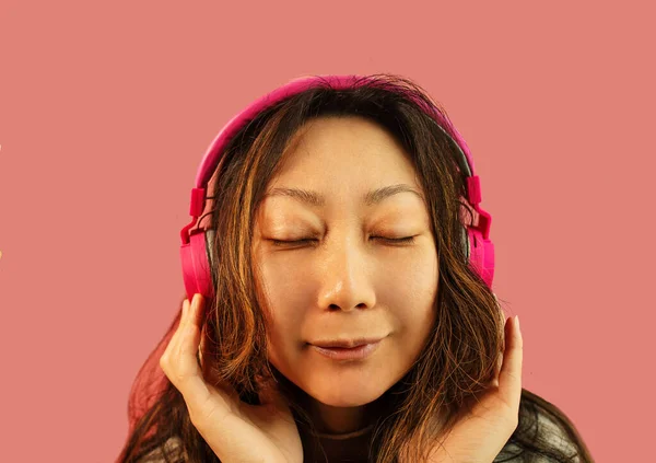 Asiatisk Pige Nyder Musik Hovedtelefoner Lyserød Baggrund Ungdomsstil Fritid - Stock-foto